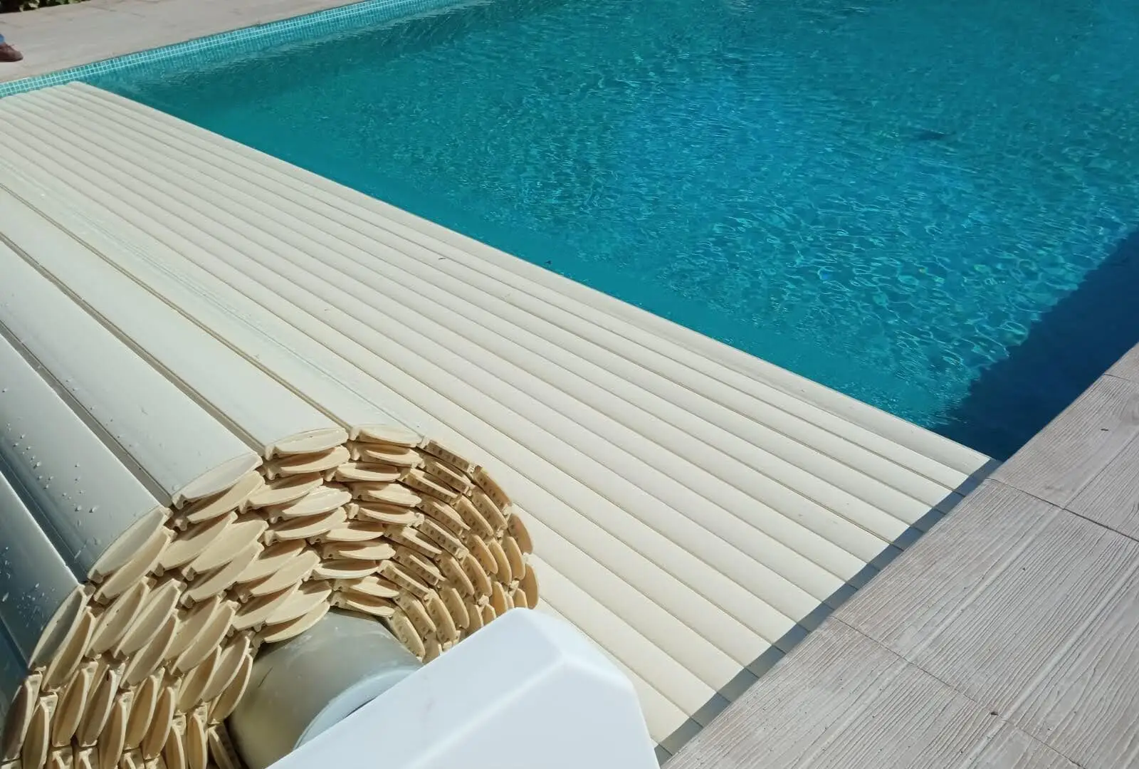 Cobertor automático de lamas enrollándose sobre una piscina
