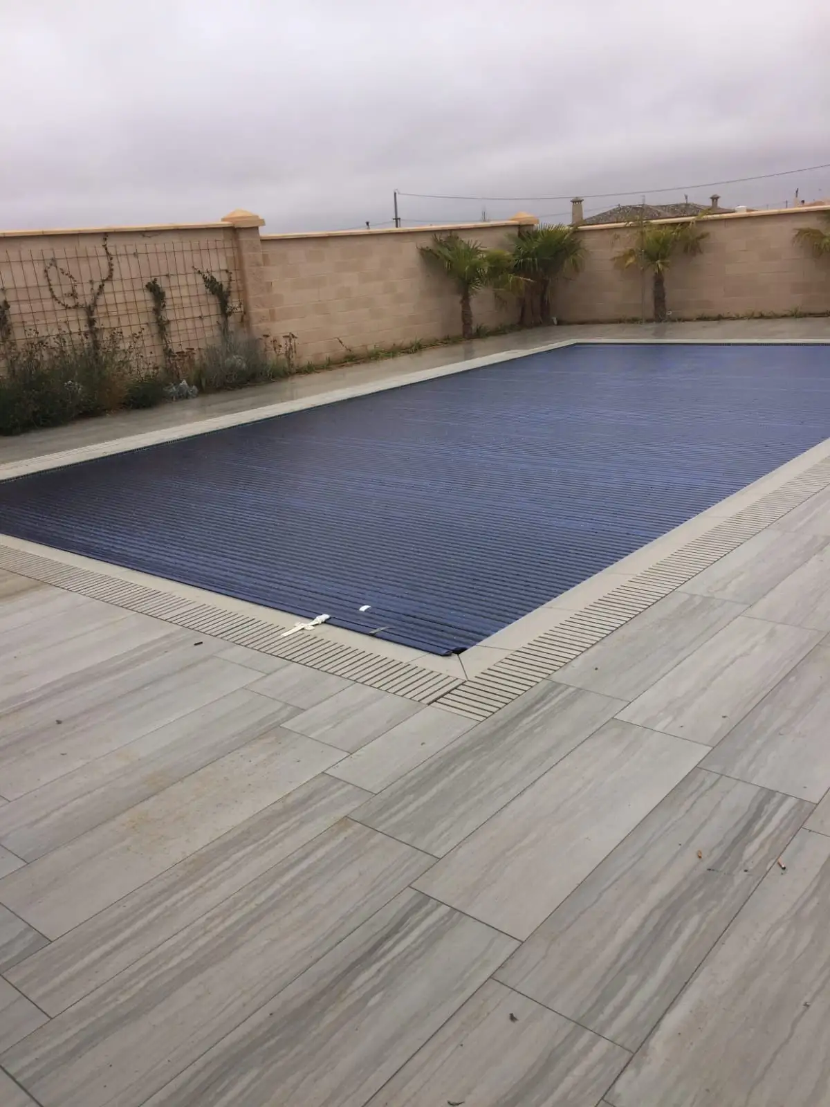 Piscina con el cobertor de lamas extendido sobre el agua