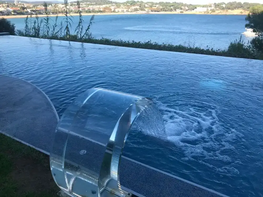 Cascada de lámina transparente cayendo sobre una piscina