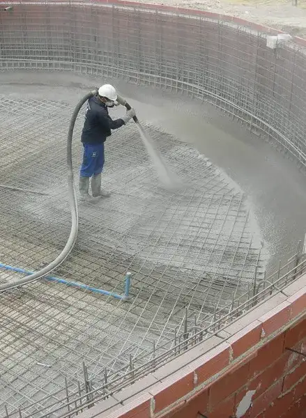 Operario proyectando hormigón sobre la armadura de acero del vaso de una piscina