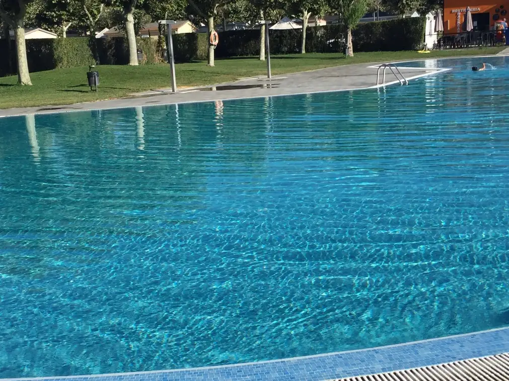 Lámina de agua limpia y transparente en una piscina grande rodeada de césped