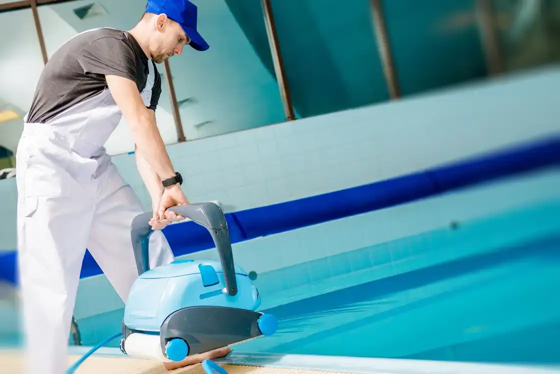 Operario metiendo un limpiafondos automático en una piscina