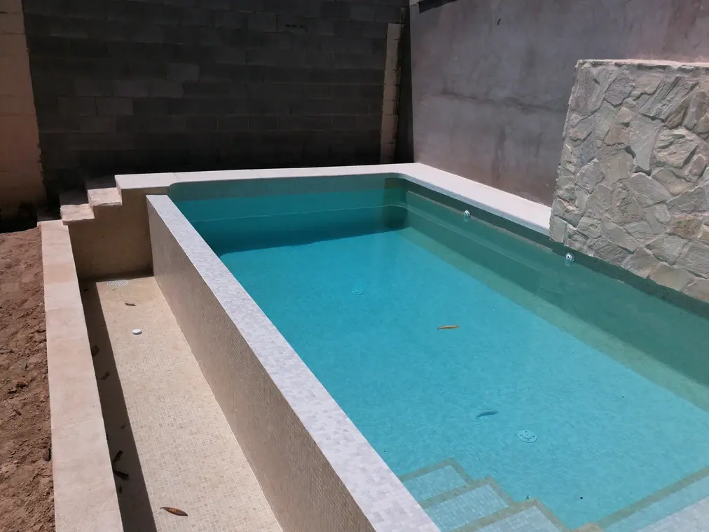 Piscina elevada con revestimiento claro y muro de piedra