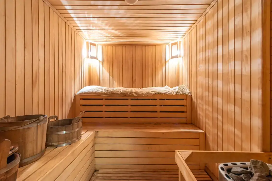 Interior de una sauna de madera con bancos y cubo
