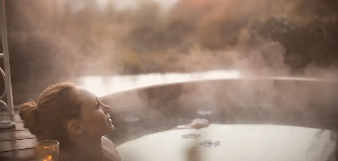 Mujer relajándose en el agua caliente de un spa con vapor