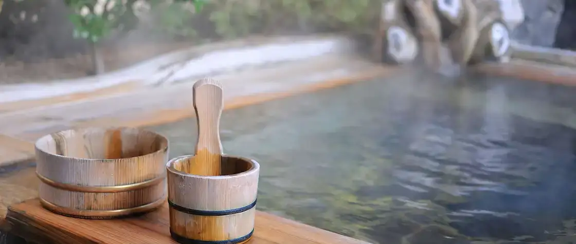 Cubo y cazo de madera junto al agua de un baño termal